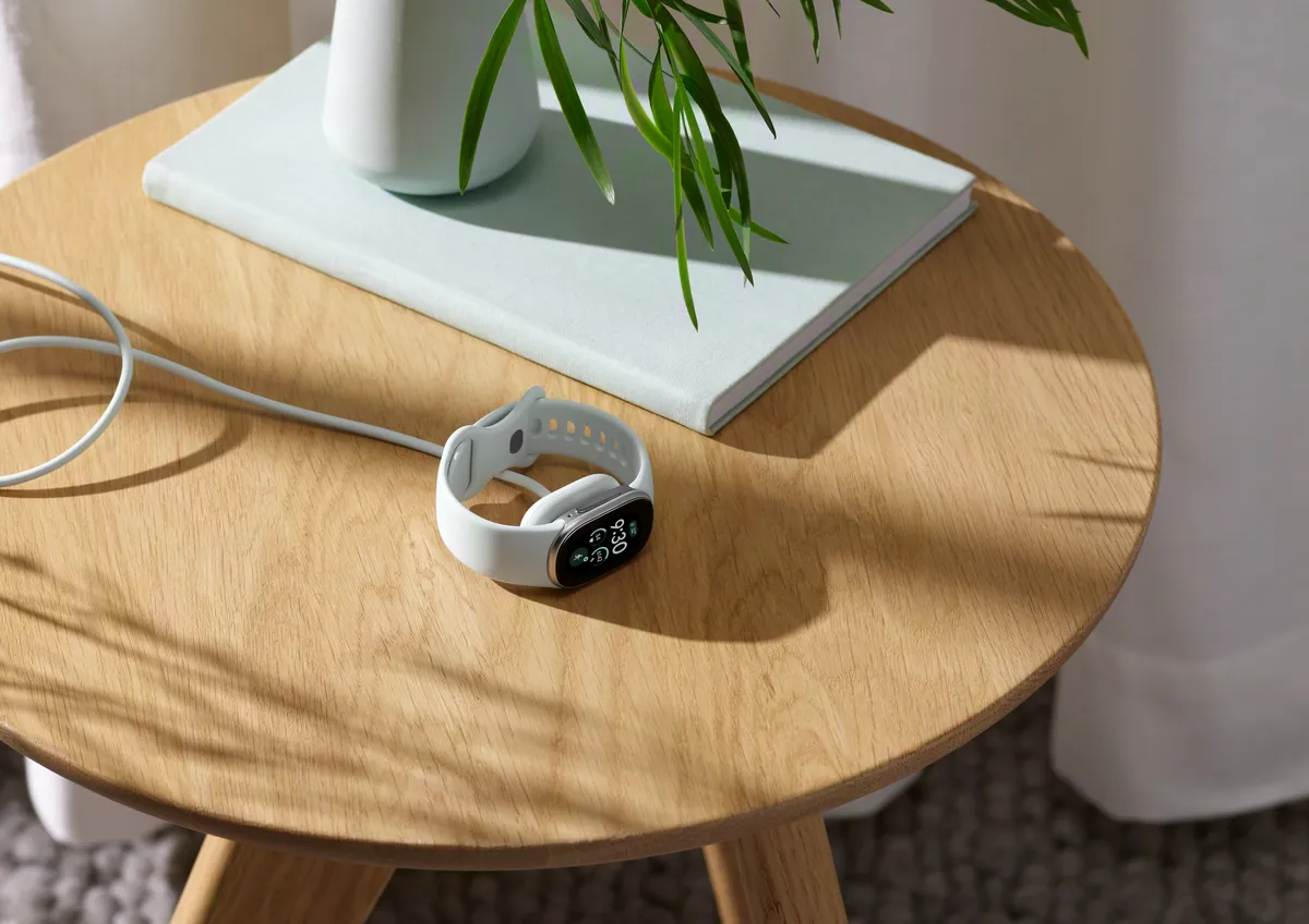 سوار Fitbit Edge متصل بالشاحن على طاولة جانبية